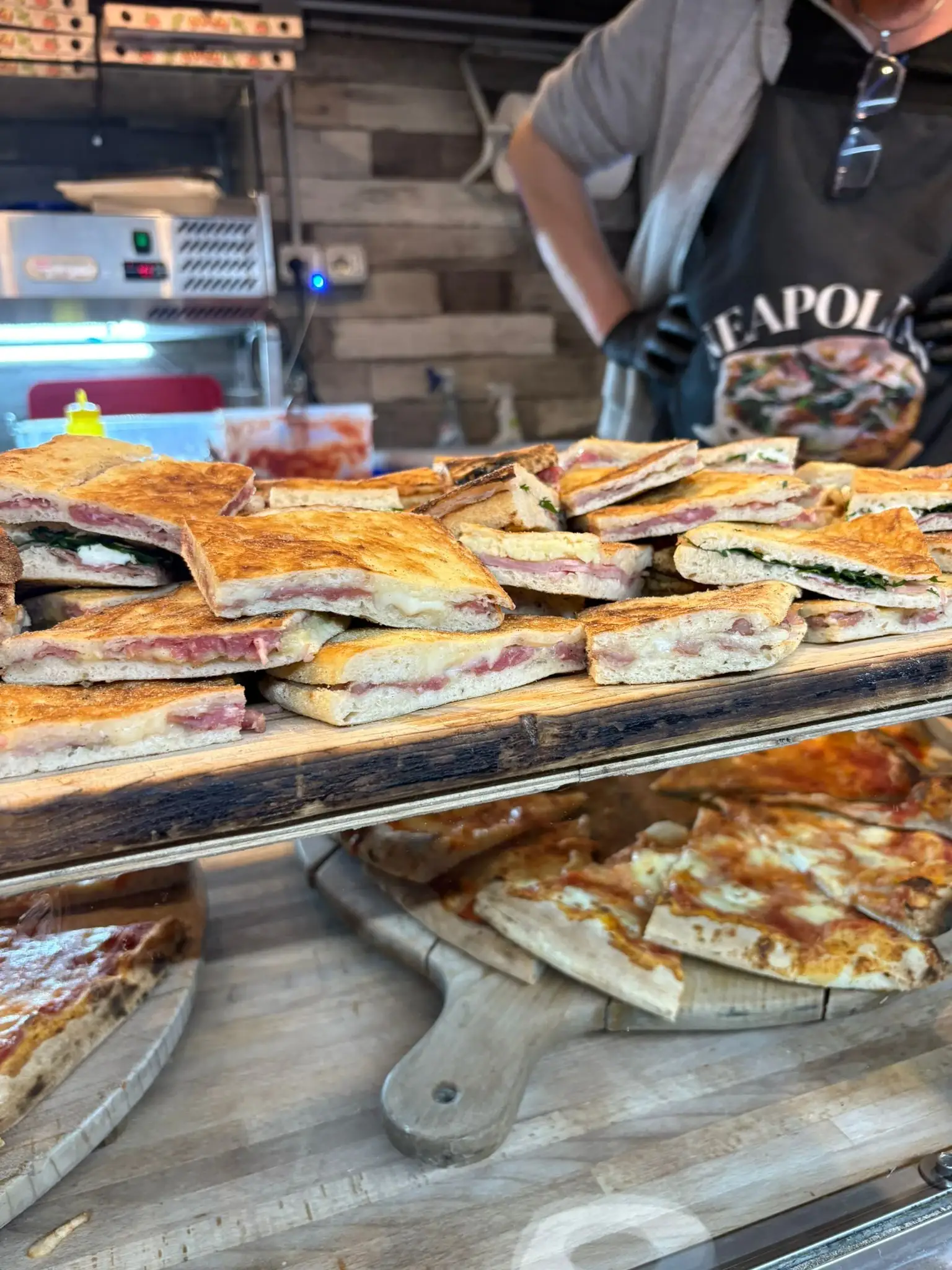Tranci di schiacciata ripiena impilati sul tagliere, al banco